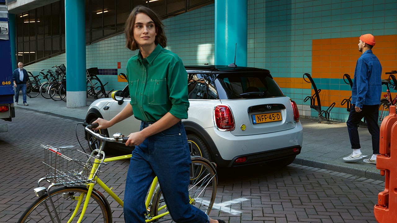 Woman with a bike in front of MINI Electric Woman with a bike in front of MINI Electric